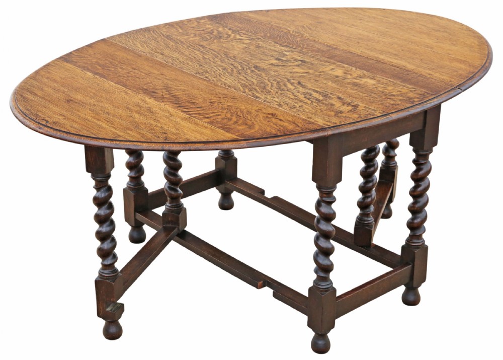 An oval oak drop-leaf dining table with barley twist turned legs and pivoting gateleg supports.