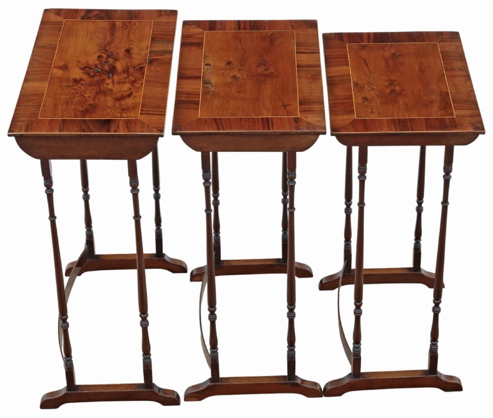 A set of three nested mahogany occasional tables featuring burr yew veneer tops with light wood inlay and slender turned legs. View VII