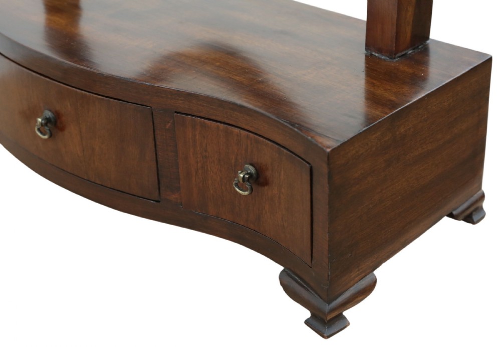 A 19th-century mahogany dressing table mirror featuring an arched shield-shaped glass frame supported by curved uprights above a serpentine base with three small drawers. View V