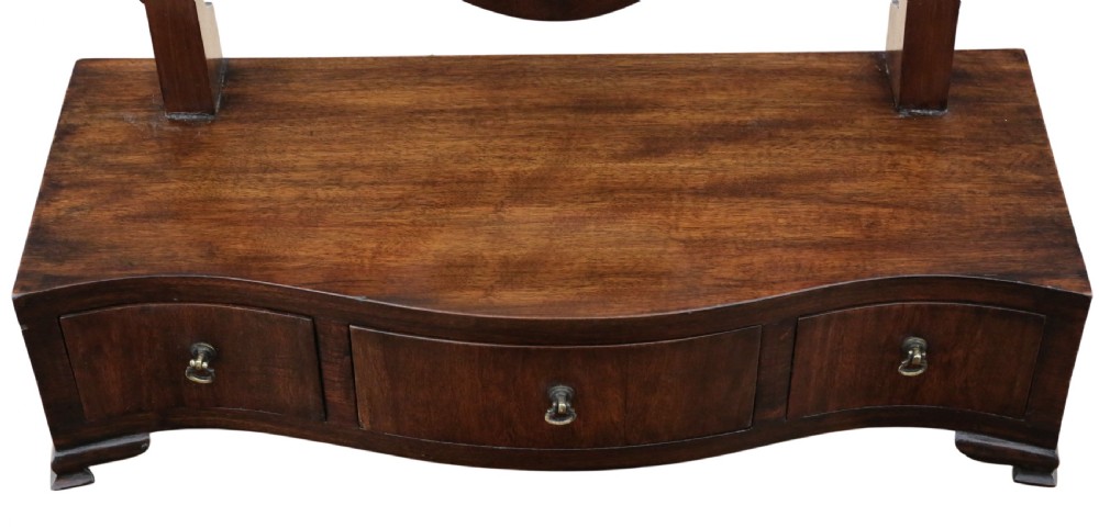 A 19th-century mahogany dressing table mirror featuring an arched shield-shaped glass frame supported by curved uprights above a serpentine base with three small drawers. View VI