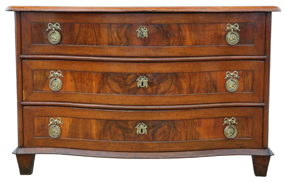 An 18th-century Continental oak and walnut chest of drawers featuring a serpentine front, crossbanded top, and three drawers with ornamental brass handles. View III