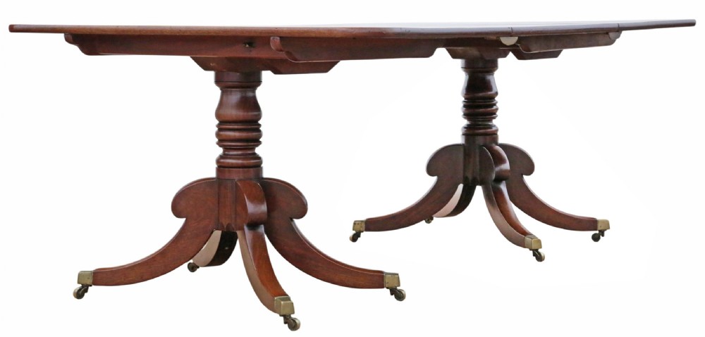An early 19th-century Georgian mahogany twin pedestal dining table featuring turned columns, splayed legs, and brass cap castors. View IV