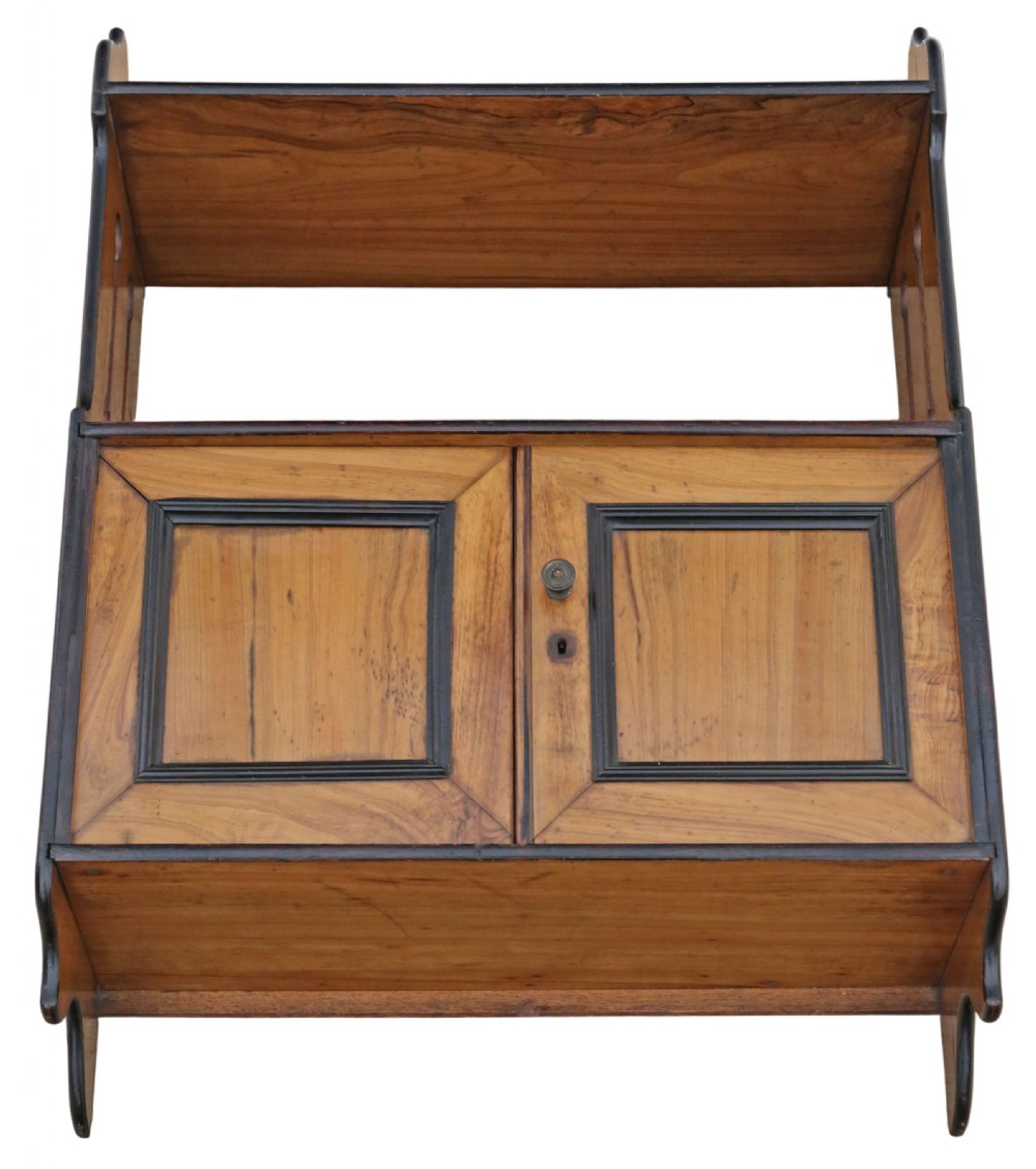 A 19th-century warm brown limewood wall cabinet featuring an upper open shelf, shaped side panels with vertical cutouts, and a lower two-door cupboard framed with dark ebonised mouldings. View VI