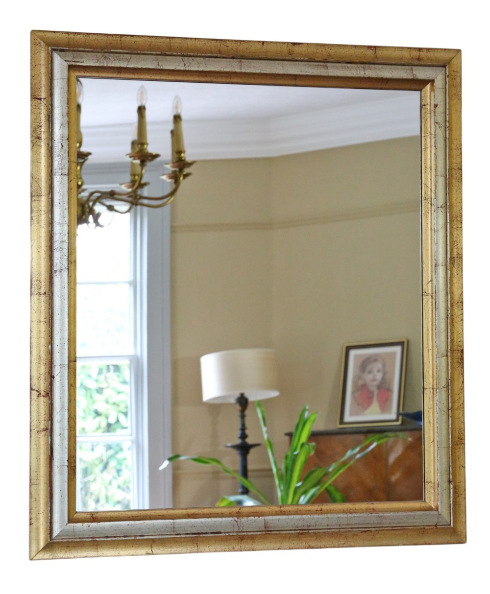 A rectangular wall mirror featuring a moulded frame with a distressed gold and silver leaf finish.