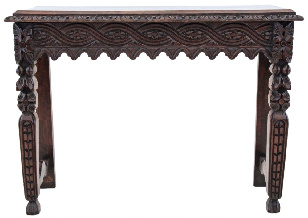 A 19th-century Victorian dark oak writing table featuring relief carving along the frieze, a scalloped apron, and carved end legs. View II