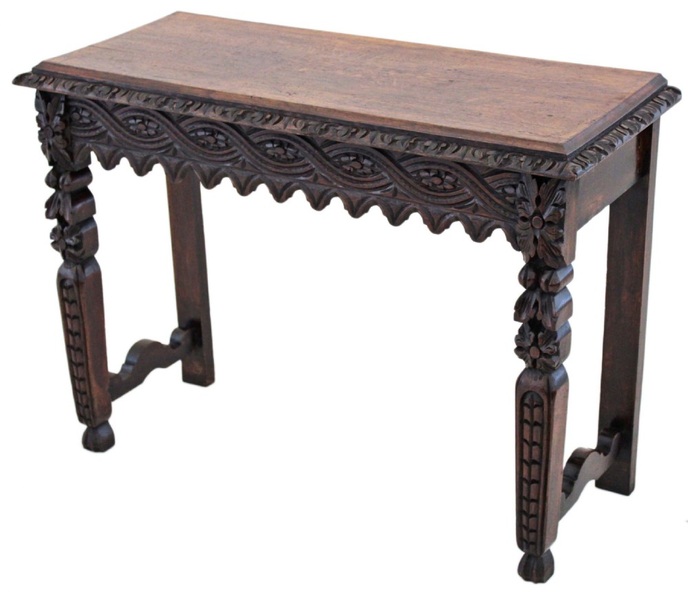 A 19th-century Victorian dark oak writing table featuring relief carving along the frieze, a scalloped apron, and carved end legs. View III