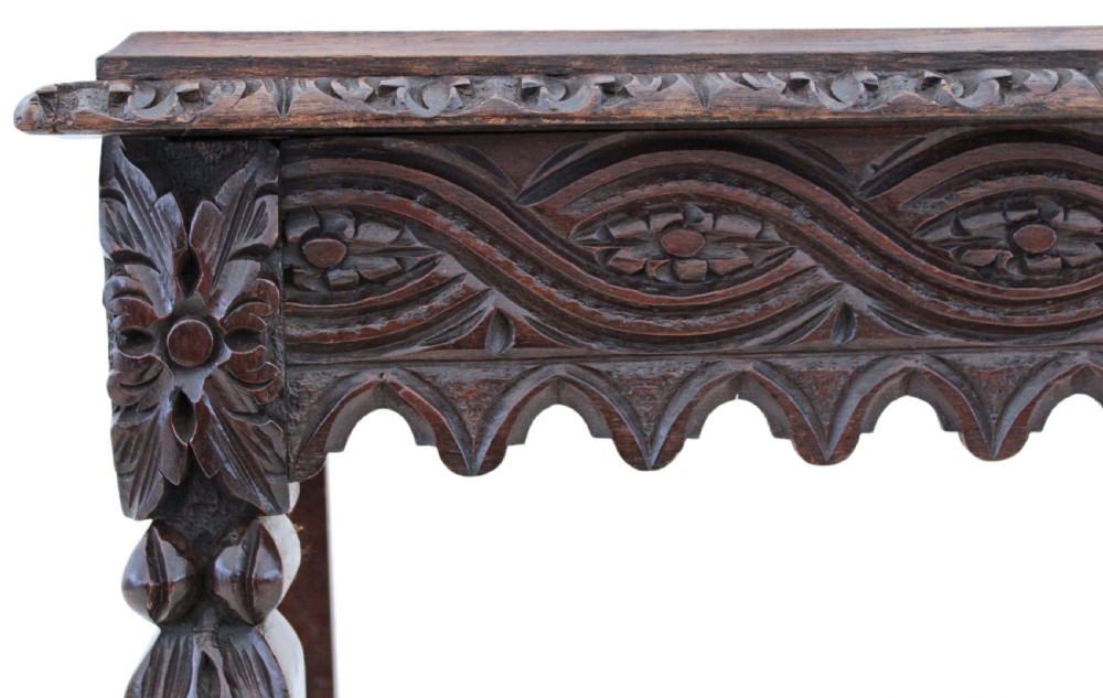 A 19th-century Victorian dark oak writing table featuring relief carving along the frieze, a scalloped apron, and carved end legs. View VIII