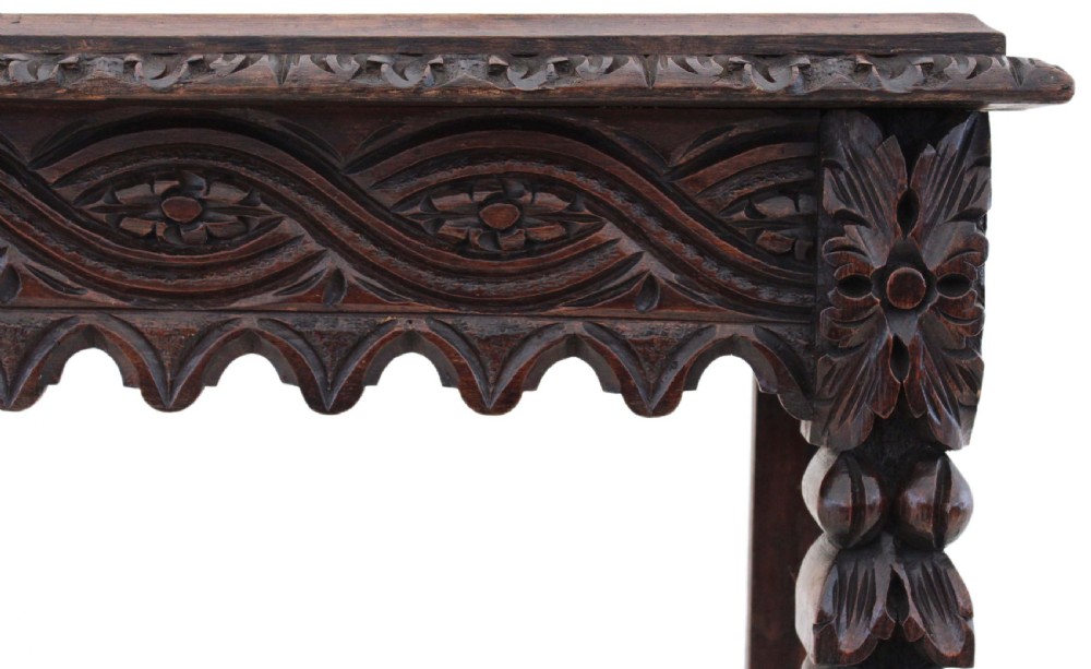 A 19th-century Victorian dark oak writing table featuring relief carving along the frieze, a scalloped apron, and carved end legs. View X