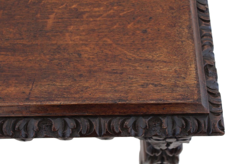 A 19th-century Victorian dark oak writing table featuring relief carving along the frieze, a scalloped apron, and carved end legs. View XI