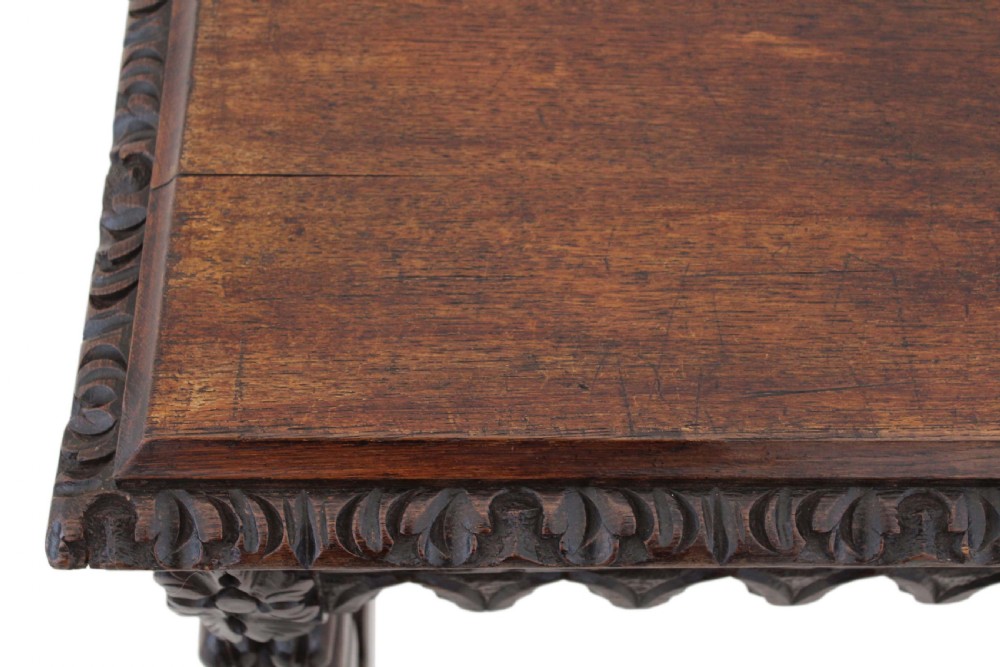 A 19th-century Victorian dark oak writing table featuring relief carving along the frieze, a scalloped apron, and carved end legs. View XII