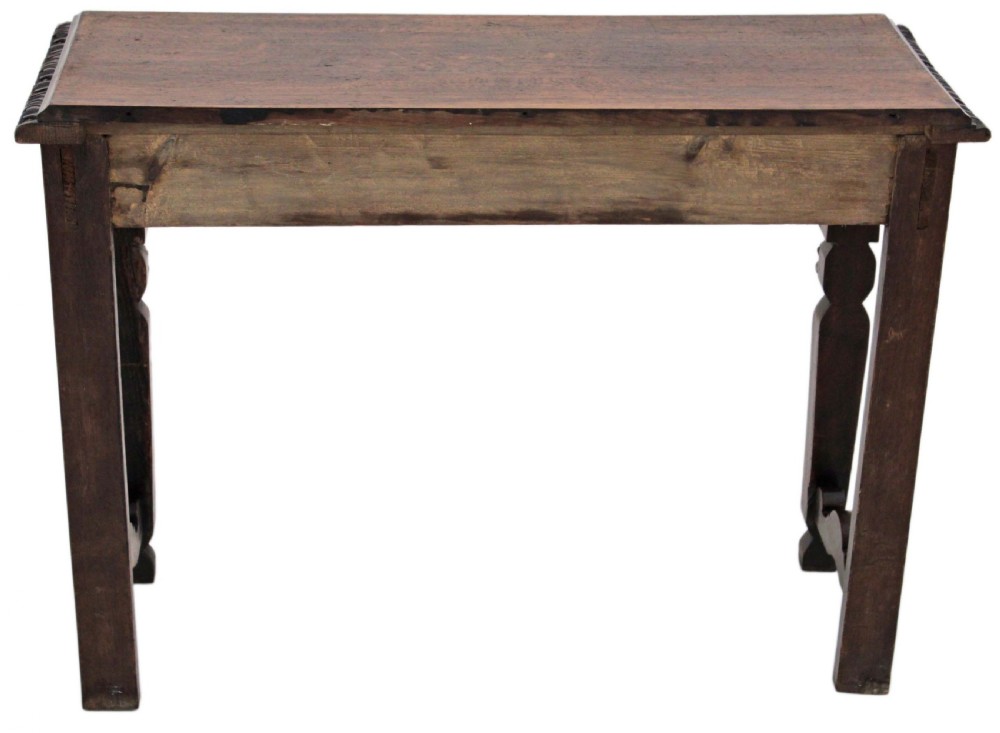 A 19th-century Victorian dark oak writing table featuring relief carving along the frieze, a scalloped apron, and carved end legs. View XIV