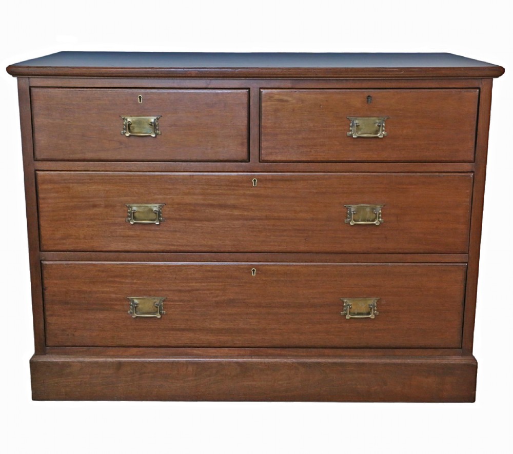 An Edwardian Art Nouveau mahogany chest of drawers featuring two short drawers above two long drawers with brass drop handles and keyhole escutcheons.