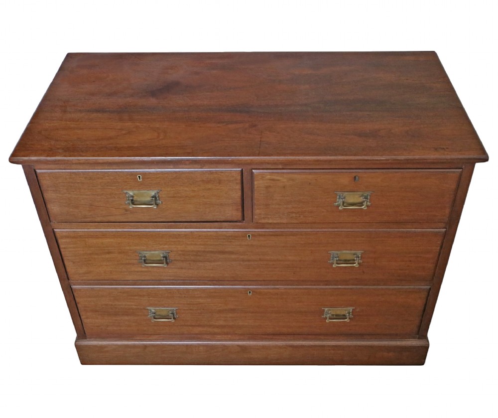 An Edwardian Art Nouveau mahogany chest of drawers featuring two short drawers above two long drawers with brass drop handles and keyhole escutcheons. View IV