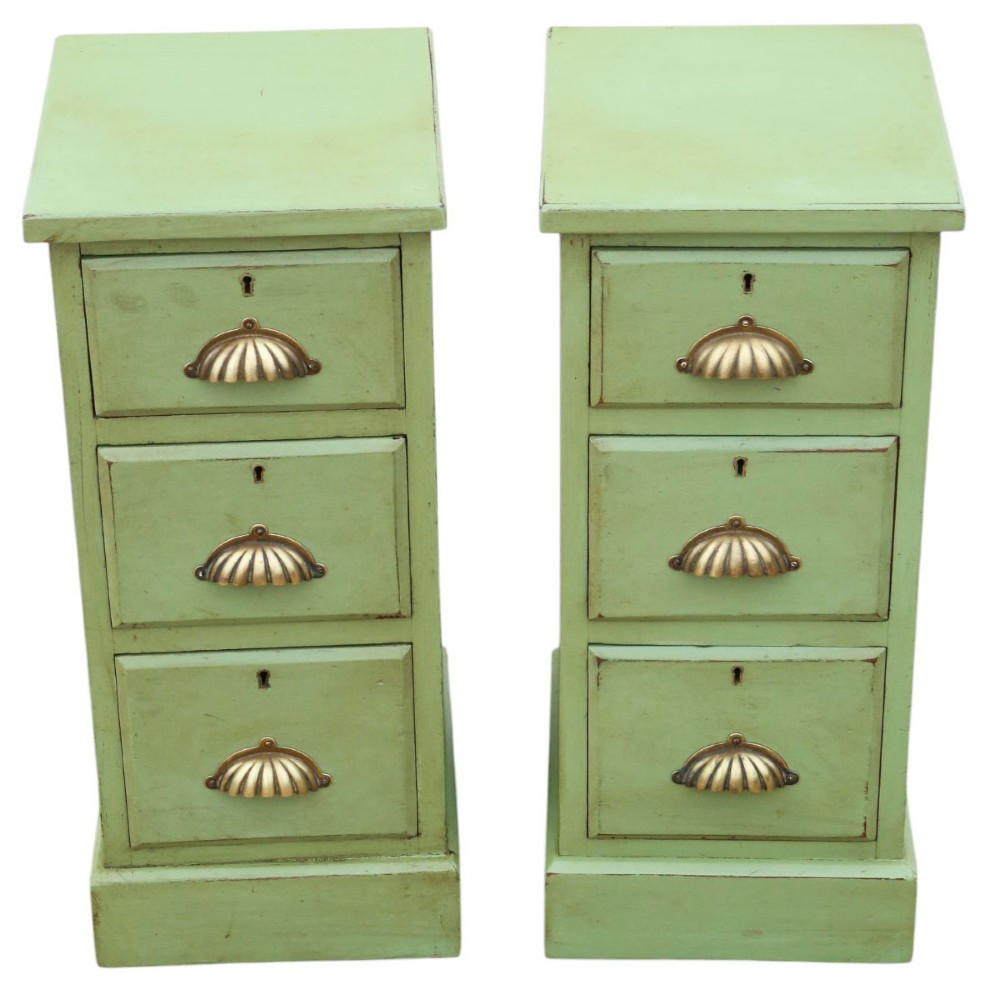A pair of matching narrow green-painted wooden bedside cabinets, each featuring three drawers with brass shell cup handles and a solid plinth base. View II