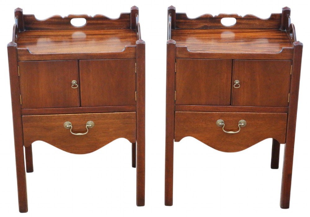 A matching pair of warm brown mahogany bedside cupboards with tray tops, double door compartments, lower drawers, and brass handles.