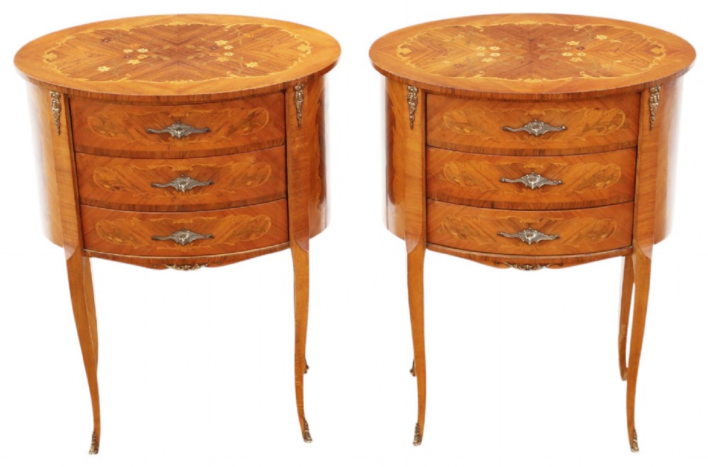 A pair of French oval bedside tables with floral marquetry inlay, three drawers, gilt mounts, and slender cabriole legs.
