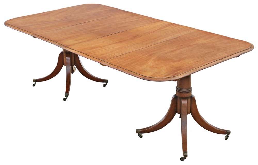 A 19th-century mahogany twin pedestal extending dining table with rounded corners, reeded edge detailing, and brass castors.