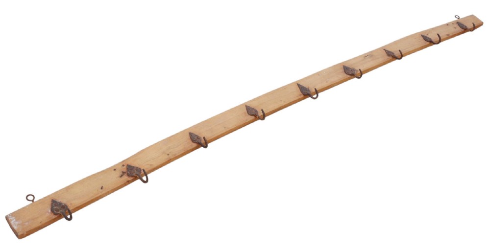 A long horizontal pine timber rail fitted with nine spaced, hand-forged wrought iron hooks with pointed backplates. View II