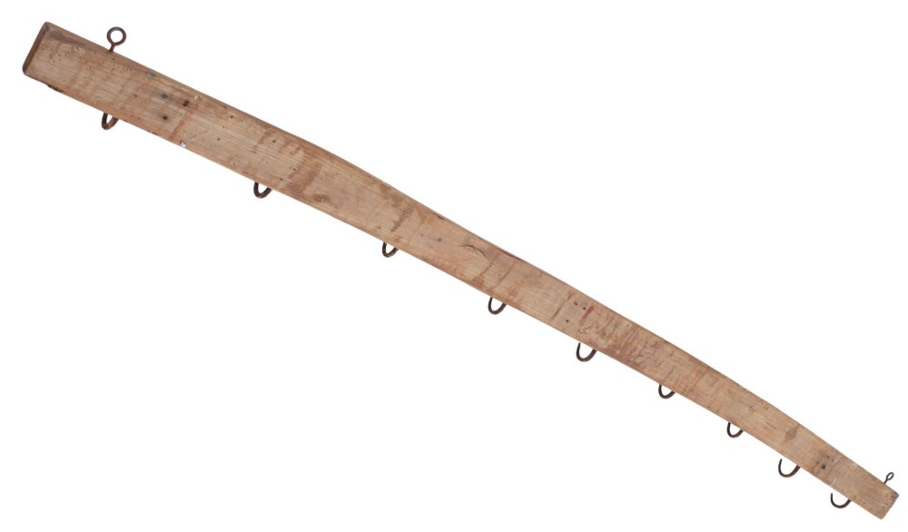 A long horizontal pine timber rail fitted with nine spaced, hand-forged wrought iron hooks with pointed backplates. View IV