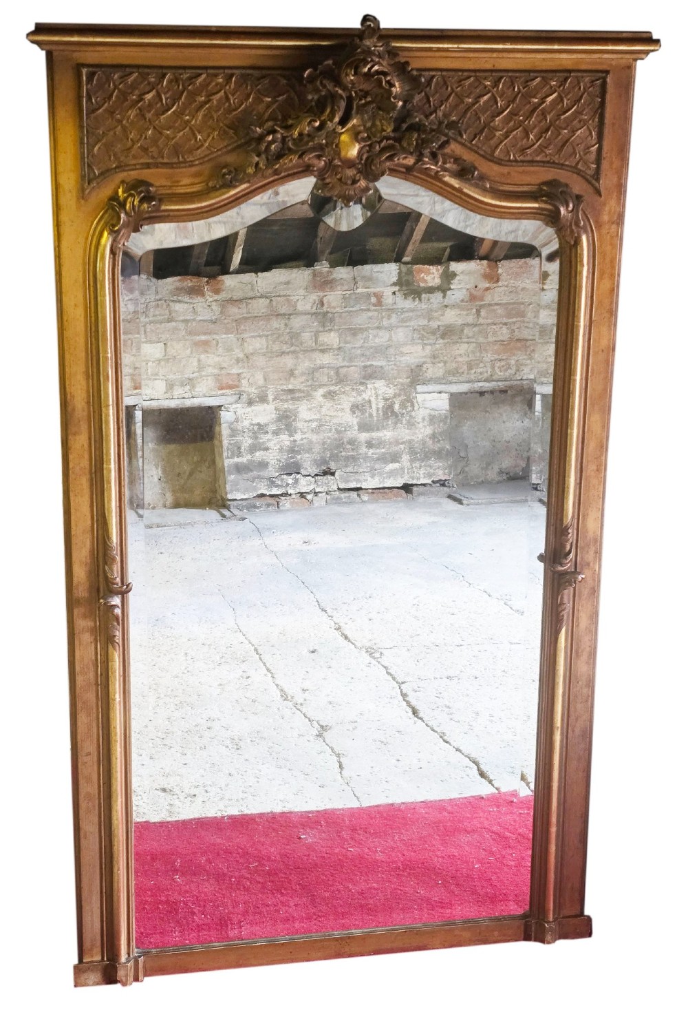 A tall 19th-century gilded overmantel mirror featuring an arched frame, top cresting, and molded lattice frieze.