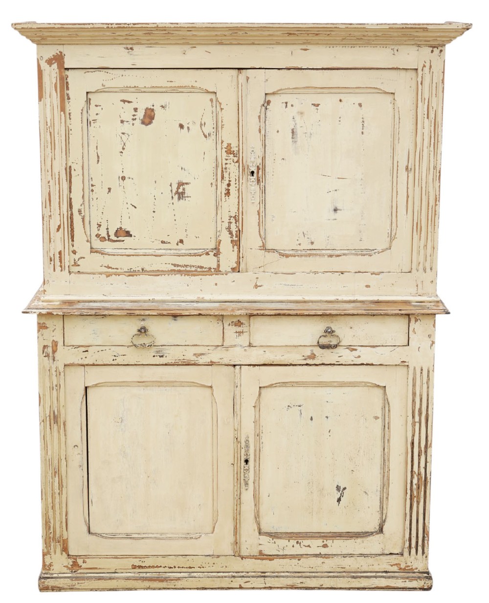 A 19th-century two-tier wooden storage cupboard painted in distressed cream, featuring fluted side details, upper and lower double doors with fielded panels, and two central drawers.