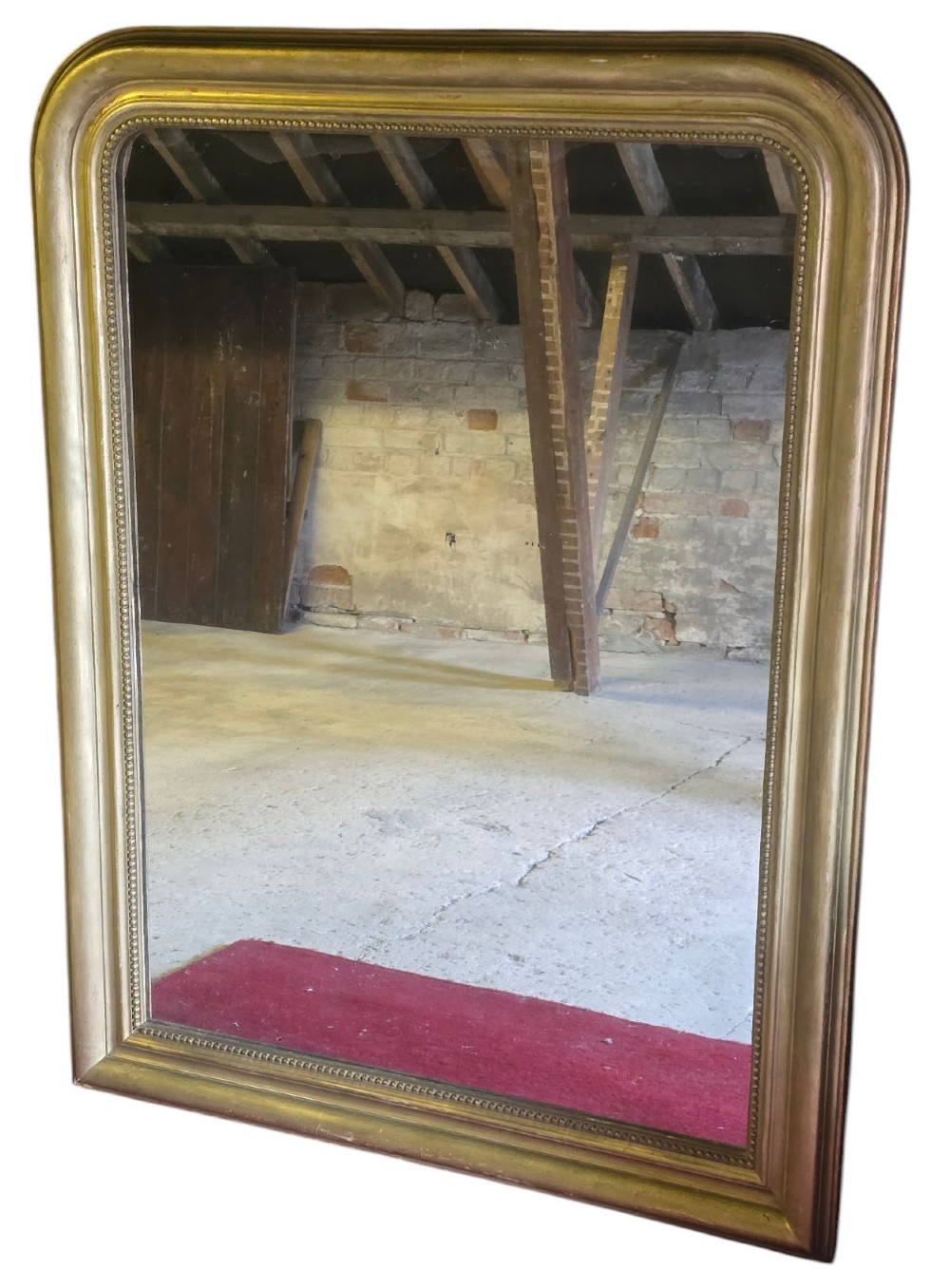 A large rectangular gilt-framed wall mirror featuring rounded top corners and a beaded inner border.