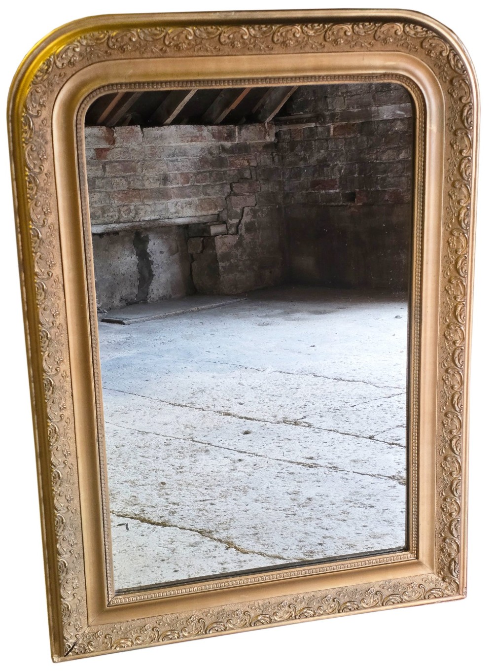 A large late nineteenth-century rectangular overmantel mirror with rounded upper corners, an intricate foliate carved gilt frame, and a beaded inner border.