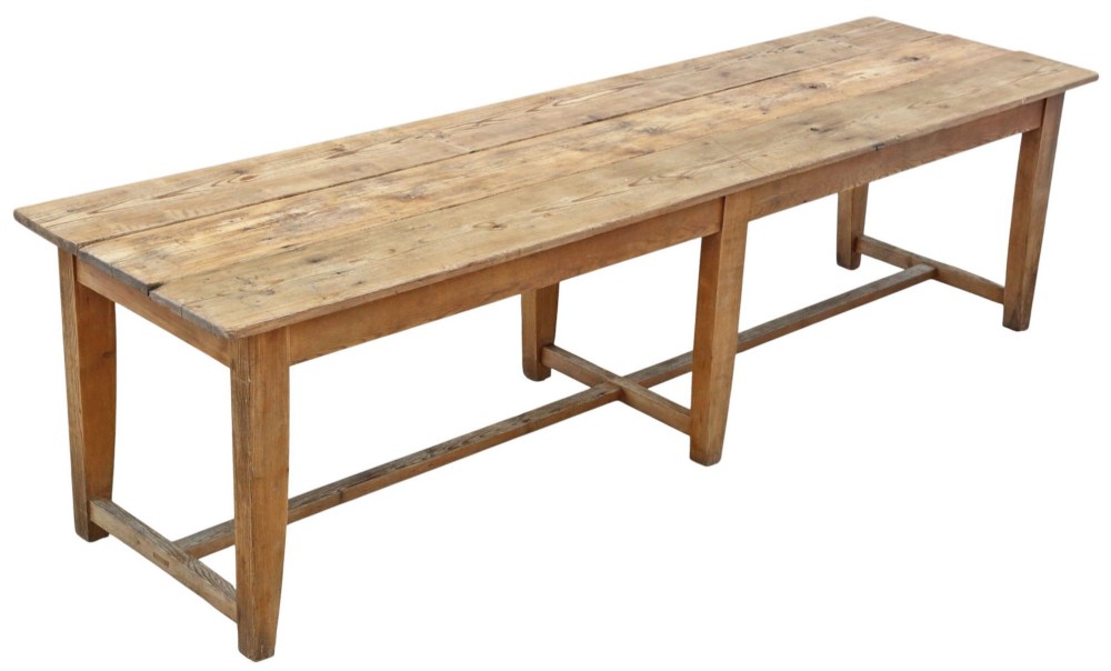 A long 19th-century pine refectory dining table featuring a three-plank top, six tapered square legs, and an H-stretcher base.
