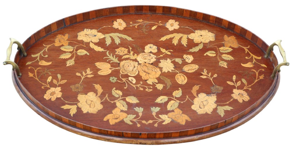 An oval mahogany serving tray decorated with floral marquetry inlay and fitted with twin brass handles.