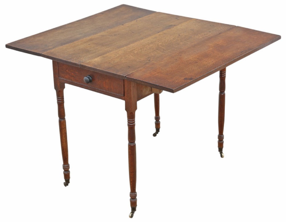 A Georgian oak drop-leaf Pembroke table featuring turned legs, a single end drawer, and brass castors.