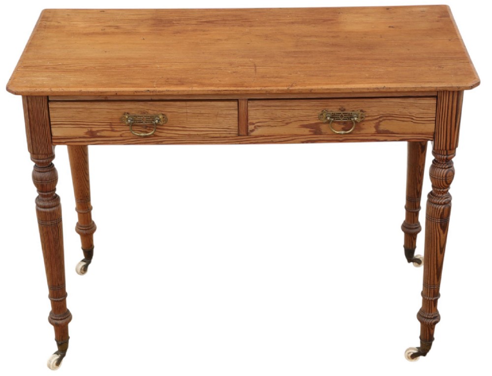A 19th-century pitch pine writing table with two drawers, brass handles, turned legs, and metal castors. View II