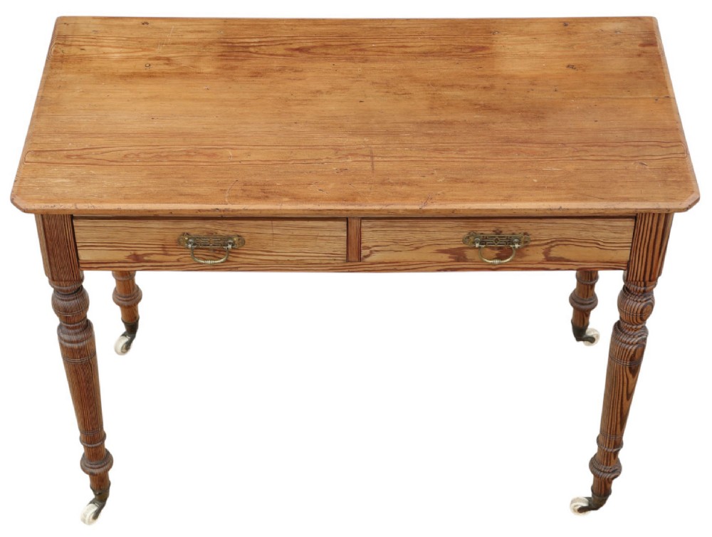 A 19th-century pitch pine writing table with two drawers, brass handles, turned legs, and metal castors. View III