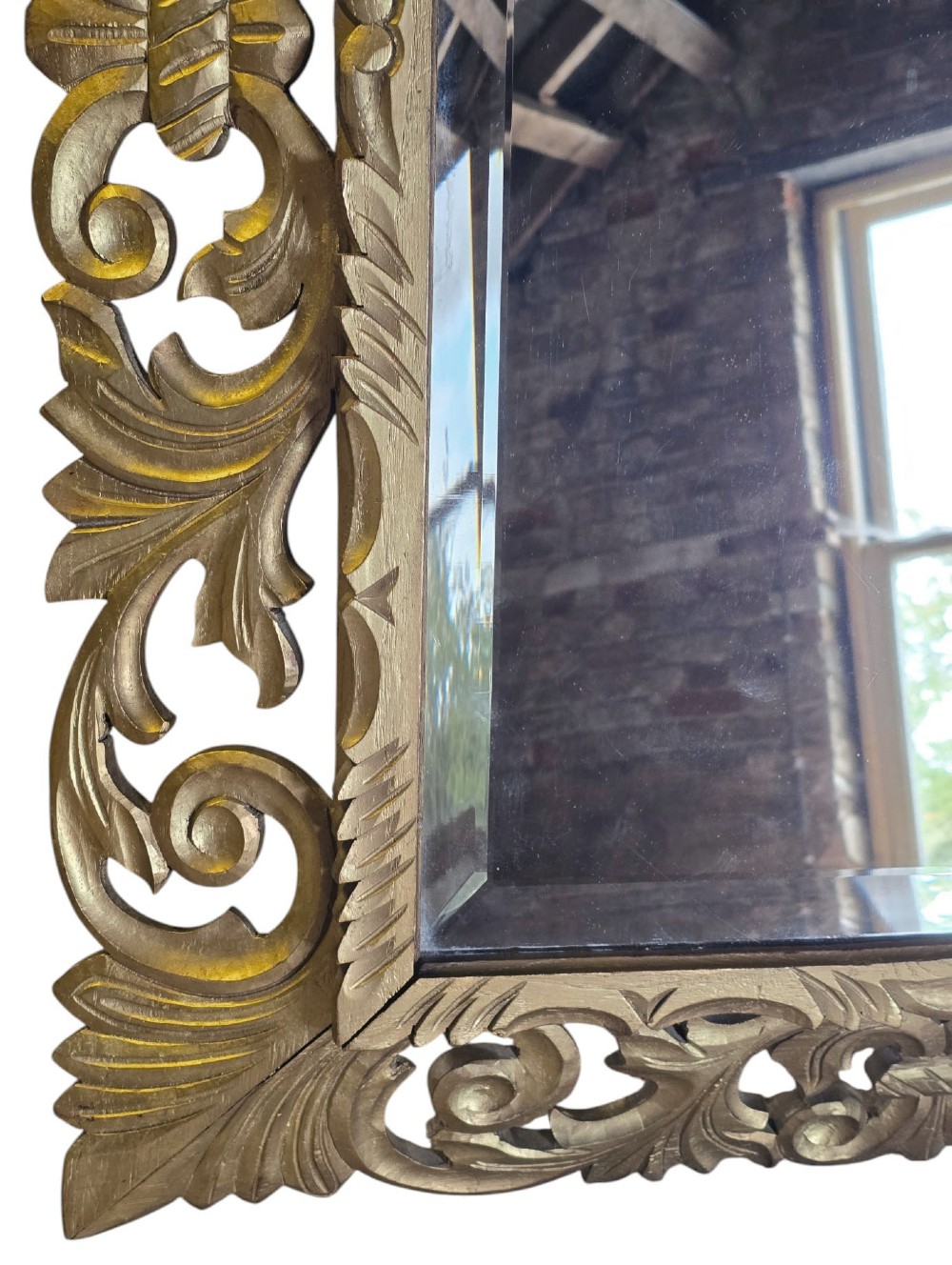 A rectangular bevelled glass mirror set within an intricately carved gold giltwood frame with openwork acanthus leaves and scrollwork. View VI