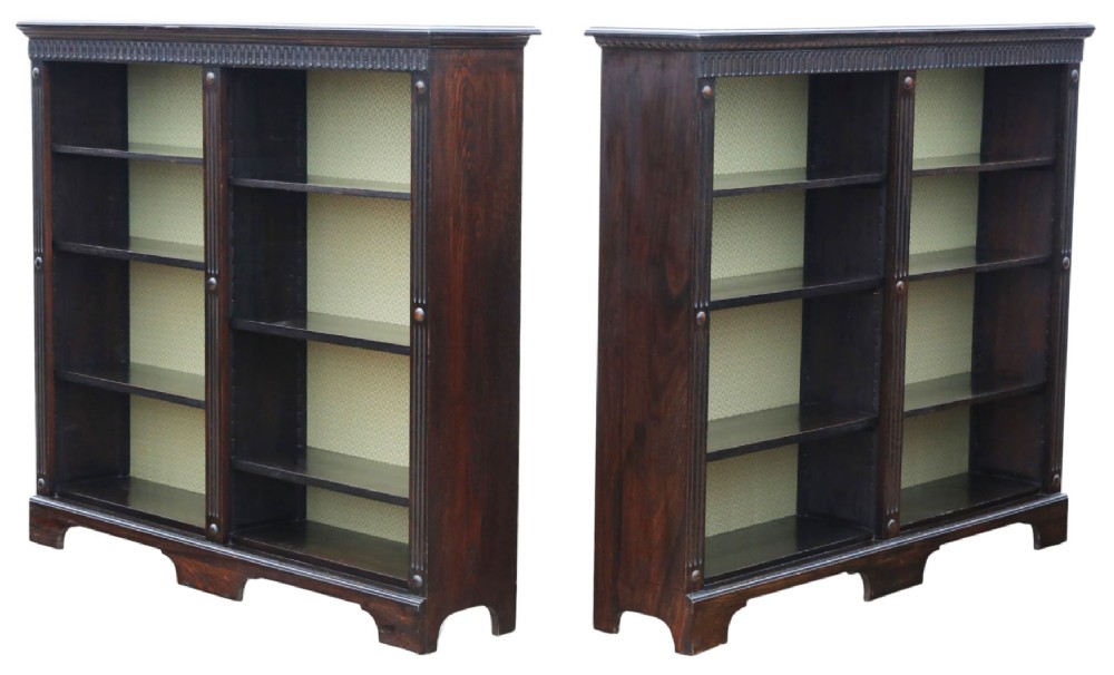 A matching pair of dark oak double-bay bookcases featuring fluted vertical trim, adjustable shelving, green pattern-lined interiors, and bracket bases. View II