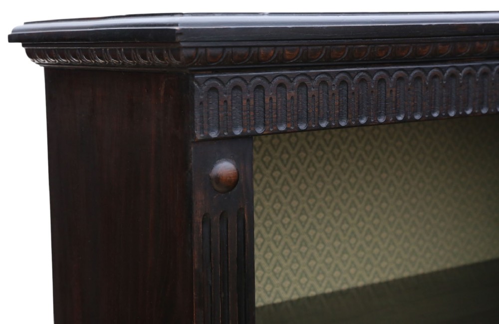 A matching pair of dark oak double-bay bookcases featuring fluted vertical trim, adjustable shelving, green pattern-lined interiors, and bracket bases. View V