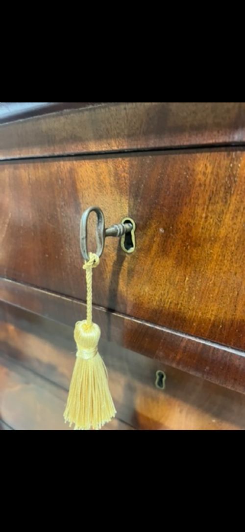 A 19th-century Biedermeier flame mahogany secretaire chest featuring a fall-front desk section, side column supports, and multiple storage drawers. View VII