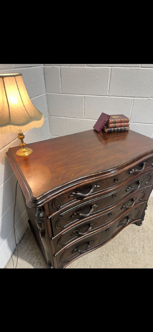A 19th-century dark walnut French chest of drawers featuring a serpentine front, four moulded drawers, and dark metal handles. View V