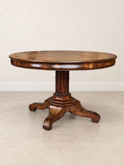 fig 1. A 19th-century circular mahogany dining table featuring a figured grain top, fluted central pedestal column, and a quadform platform base on scroll feet.