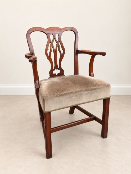 fig 1. A Georgian yew wood armchair featuring a pierced back splat, curved arms, square legs with stretchers, and a neutral velvet upholstered seat.