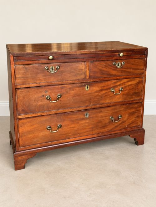 fig 1. A Georgian mahogany bachelors chest featuring a brushing slide, two short over two long drawers, brass swan-neck handles, and bracket feet.