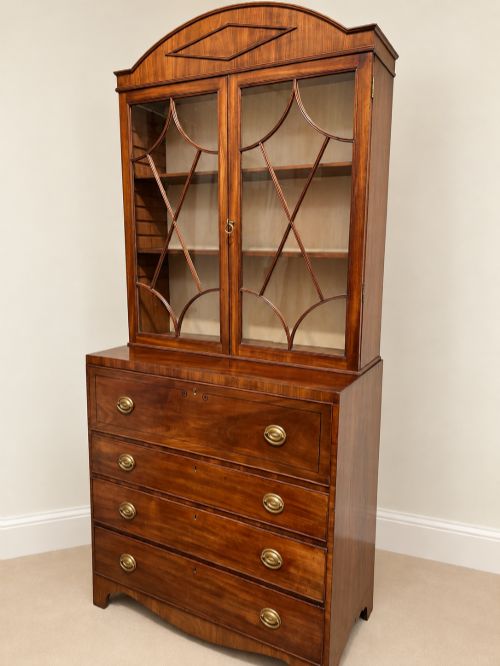 fig 1. A 19th-century mahogany secretaire bookcase featuring an arched pediment, astragal glazed upper doors, and a four-drawer base with circular brass handles.