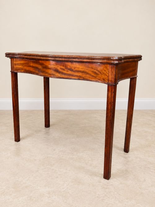 fig 1. An antique Georgian dark mahogany fold-over table featuring a serpentine-curved front apron and four straight legs.