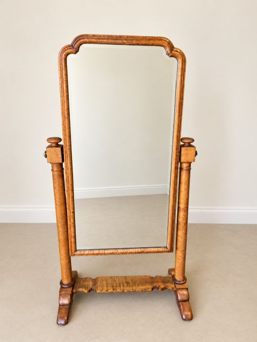 fig 1. A 19th-century full-length satin birch cheval mirror featuring an arched top frame supported by turned upright pillars on splayed legs.