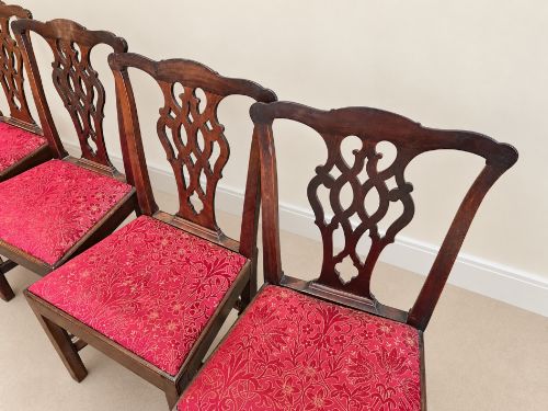 fig 1. A set of six dark mahogany Georgian dining chairs featuring intricately pierced back splats and red patterned fabric drop-in seats.