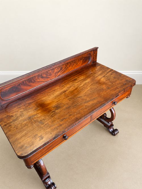 fig 1. A 19th-century mahogany writing desk with a low gallery back, two frieze drawers, carved scroll trestle legs, and a turned stretcher.