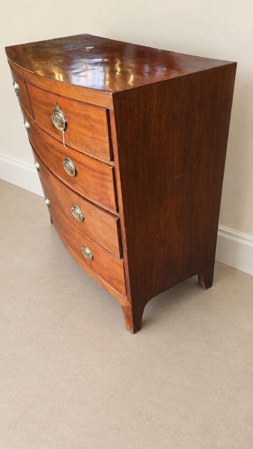 A nineteenth-century mahogany bowfront chest of drawers featuring two short drawers above three long graduated drawers with oval brass handles and splayed bracket feet. View III