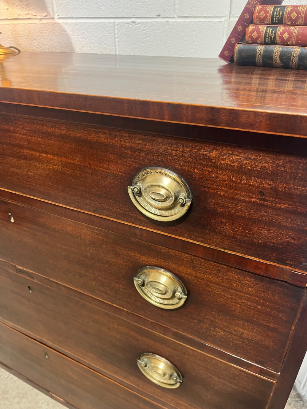 A nineteenth-century mahogany chest of drawers featuring four graduated drawers with oval brass handles and bracket feet. View VII