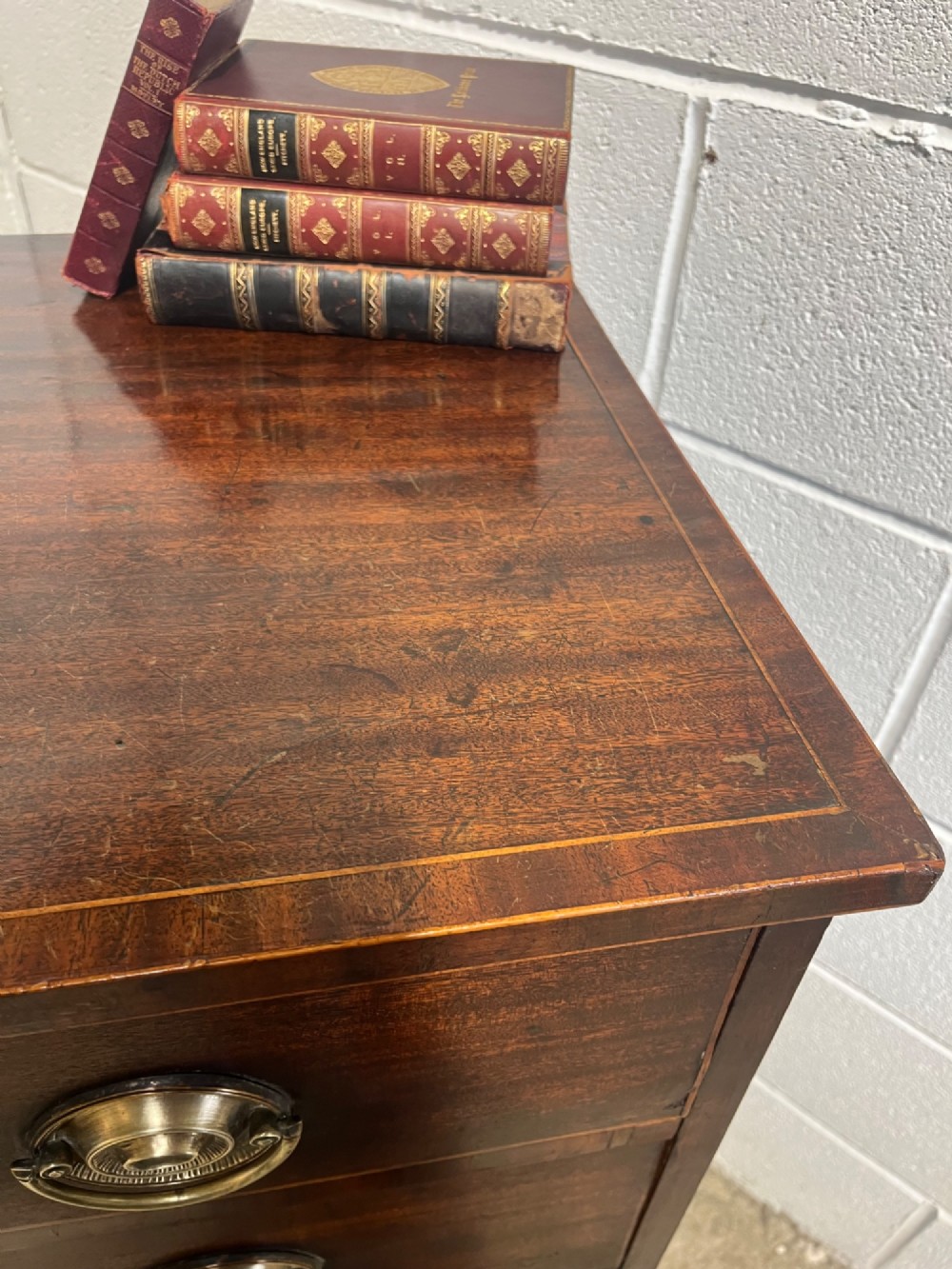 A nineteenth-century mahogany chest of drawers featuring four graduated drawers with oval brass handles and bracket feet. View VIII