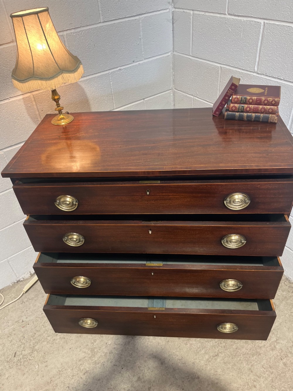 A nineteenth-century mahogany chest of drawers featuring four graduated drawers with oval brass handles and bracket feet. View IX
