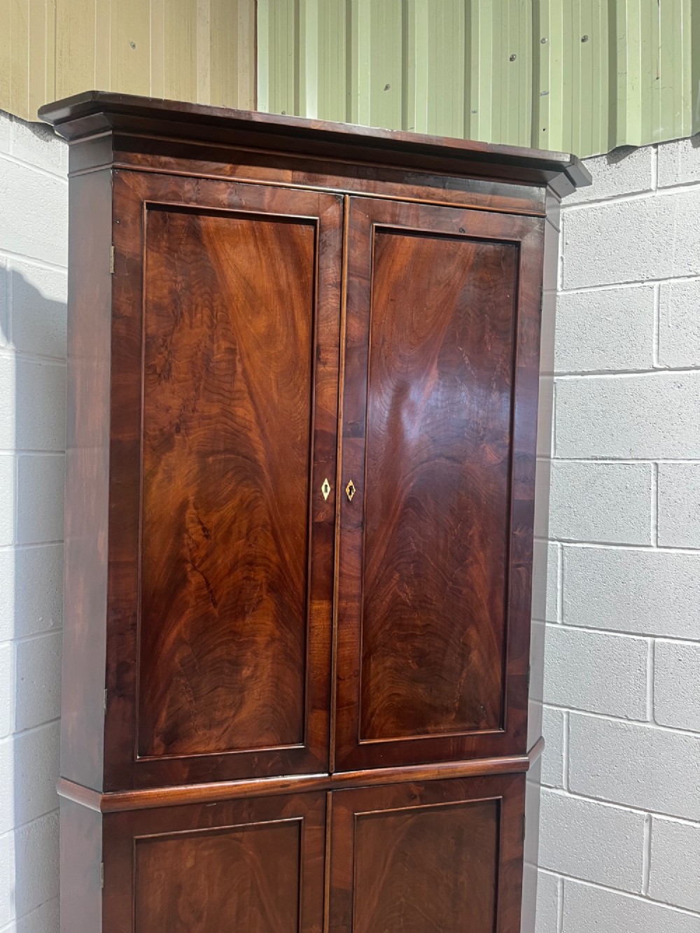A tall Georgian floor-standing corner cupboard made of dark flame mahogany, featuring two upper doors and two lower doors with brass diamond escutcheons. View VI